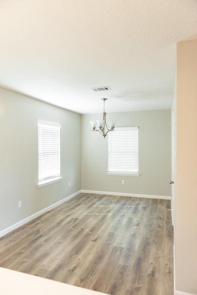 unfurnished room with a notable chandelier and hardwood / wood-style floors