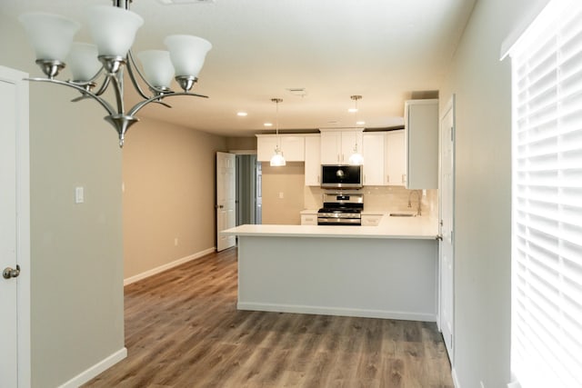 kitchen with pendant lighting, kitchen peninsula, sink, white cabinetry, and stainless steel appliances