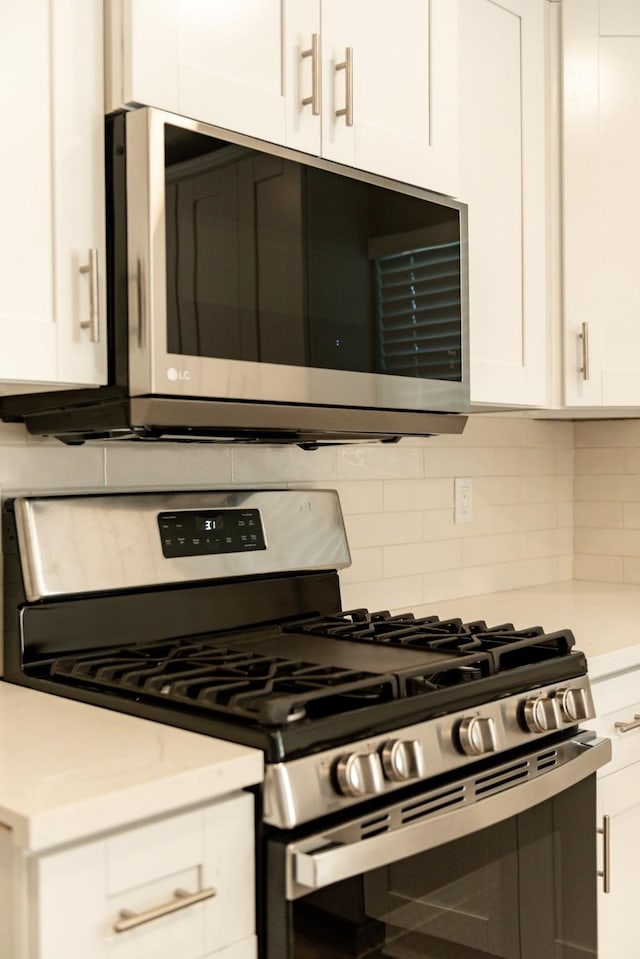 kitchen with white cabinets, backsplash, and appliances with stainless steel finishes