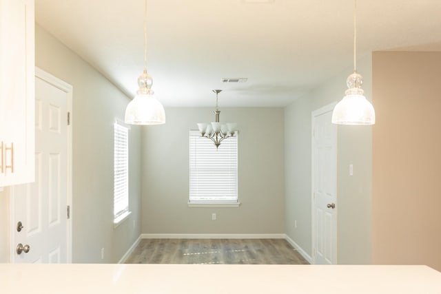 unfurnished dining area with light hardwood / wood-style floors and a notable chandelier