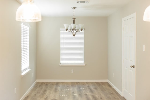 empty room featuring light hardwood / wood-style flooring and a notable chandelier