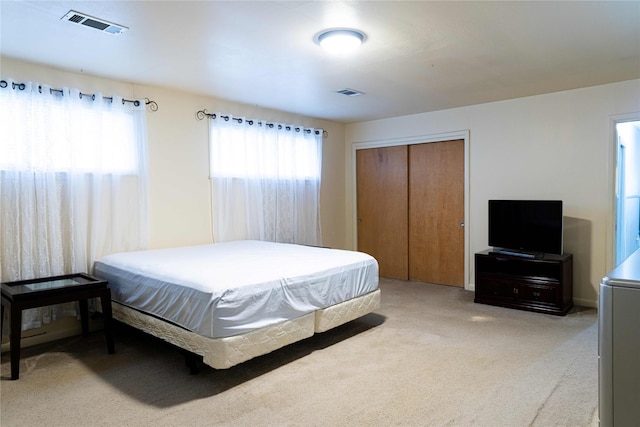 bedroom featuring light colored carpet and a closet