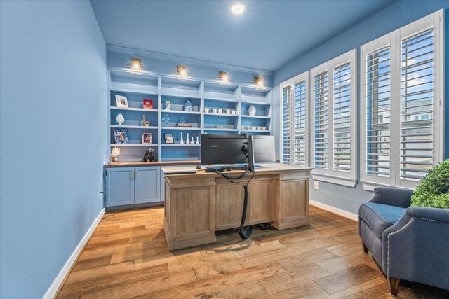 office space with built in shelves and light wood-type flooring