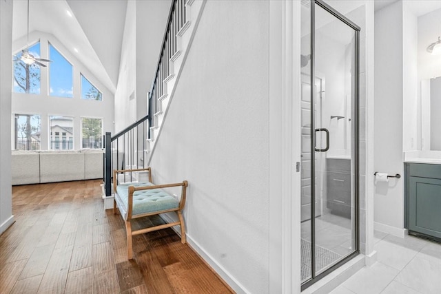 full bathroom featuring high vaulted ceiling, wood finished floors, a shower stall, baseboards, and vanity