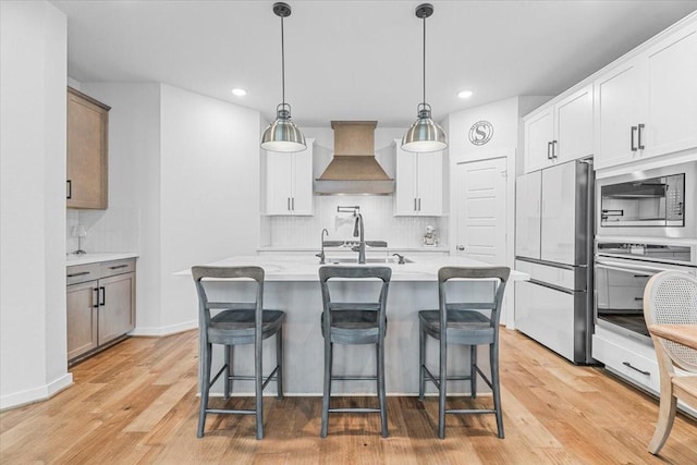 kitchen featuring custom range hood, stainless steel appliances, light wood-style floors, light countertops, and decorative backsplash