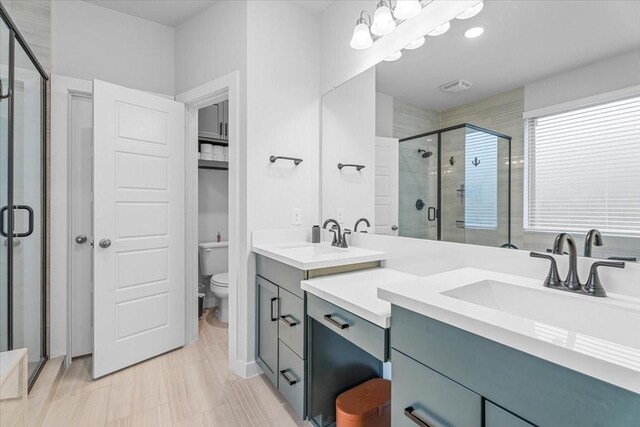 bathroom featuring a shower with shower door, toilet, and vanity