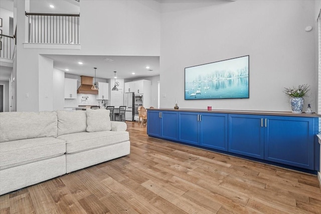 living room with a high ceiling and light hardwood / wood-style flooring