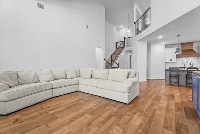 living room with a towering ceiling and light hardwood / wood-style floors