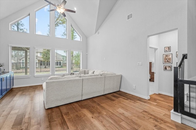 unfurnished living room featuring baseboards, visible vents, high vaulted ceiling, ceiling fan, and light wood-style floors