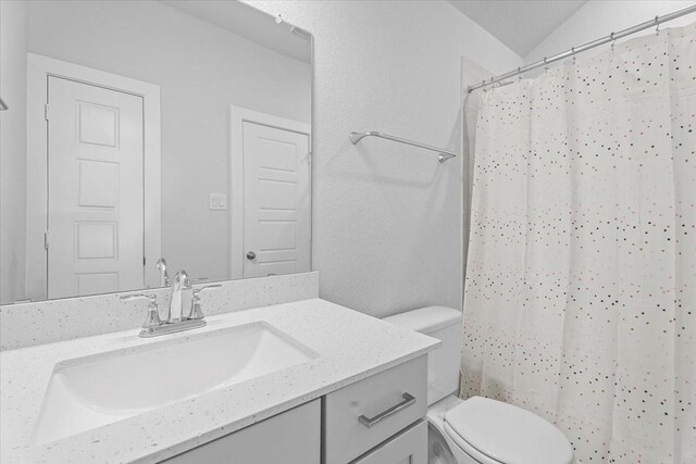 bathroom with toilet, vanity, lofted ceiling, and walk in shower