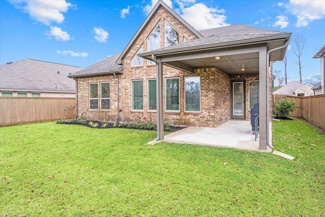 rear view of property with brick siding, a shingled roof, a fenced backyard, a yard, and a patio area