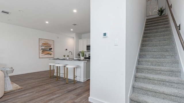 staircase with sink and wood-type flooring