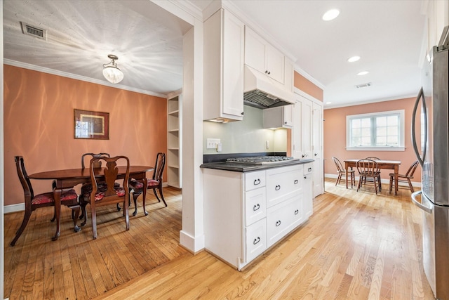 kitchen with light wood-type flooring, ornamental molding, white cabinets, and stainless steel refrigerator