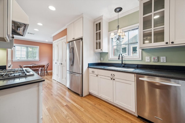 kitchen featuring pendant lighting, white cabinetry, stainless steel appliances, sink, and crown molding