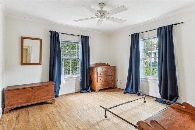 bedroom featuring light wood-type flooring, ceiling fan, ornamental molding, and multiple windows