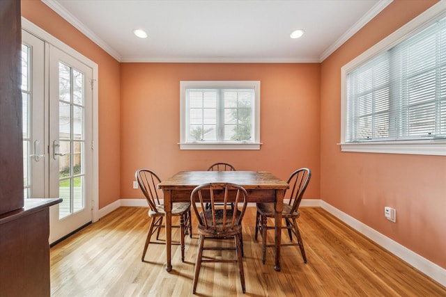 dining space with light wood-type flooring, a wealth of natural light, and ornamental molding