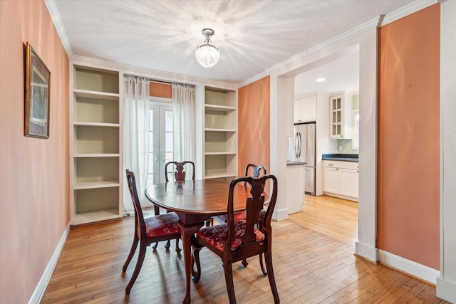 dining area featuring ornamental molding, light hardwood / wood-style flooring, and built in shelves