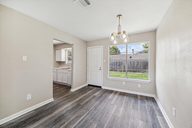 unfurnished dining area featuring dark wood-type flooring, sink, and a chandelier