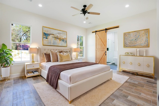 bedroom with ceiling fan, connected bathroom, and a barn door