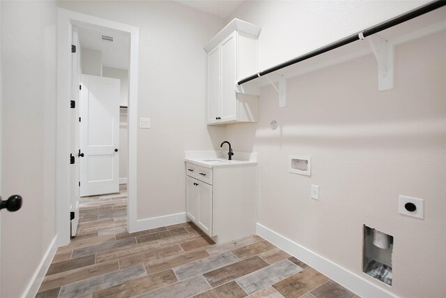 clothes washing area with hookup for a gas dryer, electric dryer hookup, washer hookup, cabinets, and sink