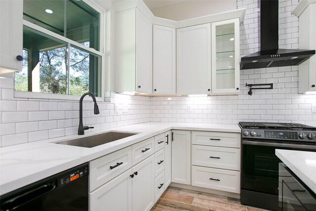 kitchen with wall chimney range hood, sink, black dishwasher, white cabinetry, and gas range