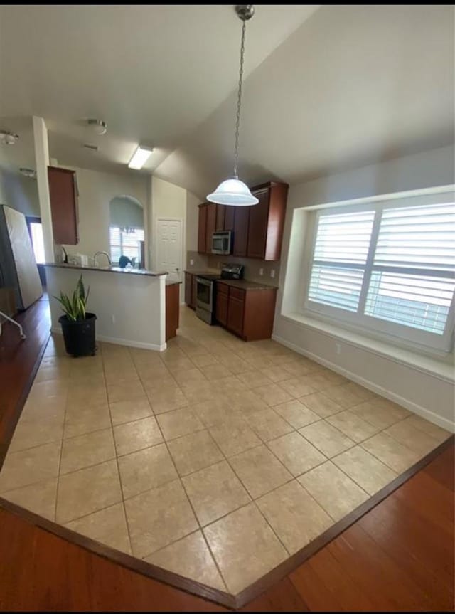 kitchen with light tile patterned floors, pendant lighting, appliances with stainless steel finishes, and lofted ceiling