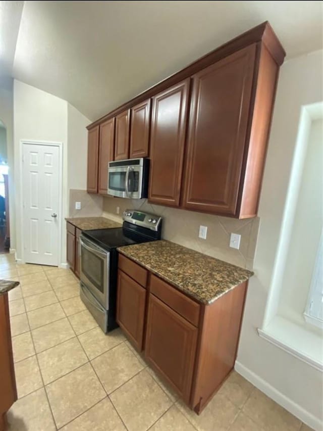 kitchen with dark stone countertops, stainless steel appliances, and light tile patterned flooring