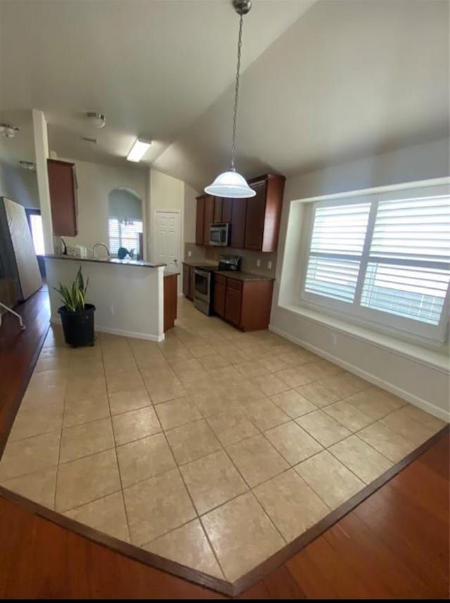 kitchen featuring vaulted ceiling, appliances with stainless steel finishes, light tile patterned flooring, and pendant lighting