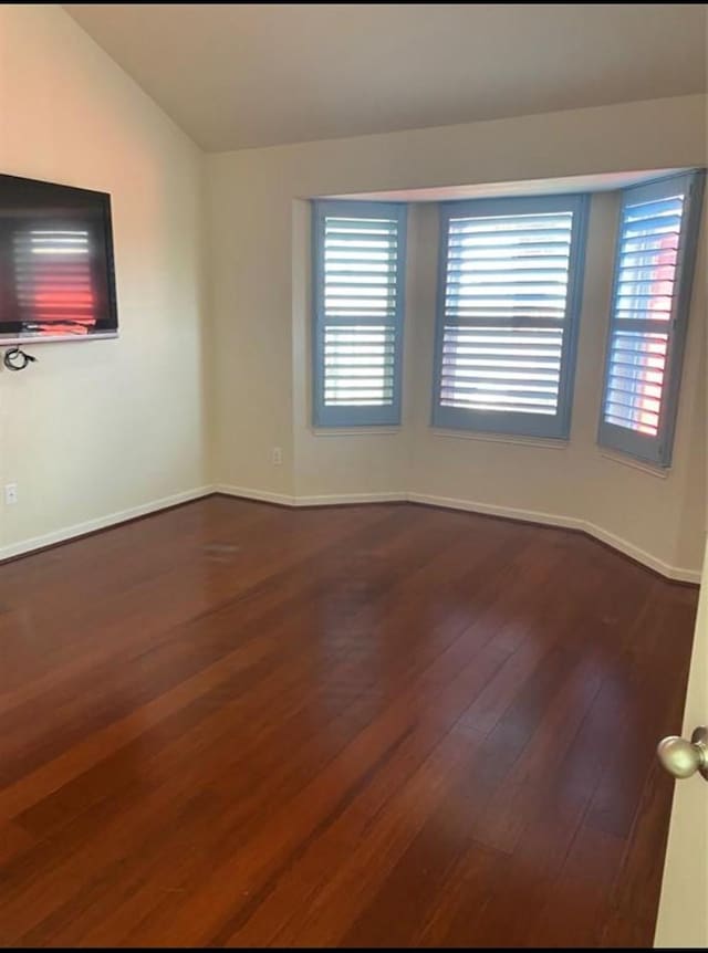 unfurnished room with wood-type flooring and vaulted ceiling