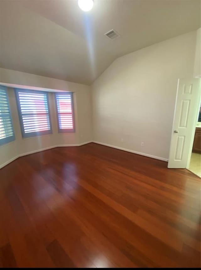 unfurnished room featuring wood-type flooring and lofted ceiling