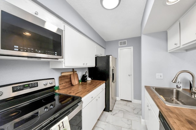 kitchen featuring white cabinets, butcher block countertops, sink, and stainless steel appliances