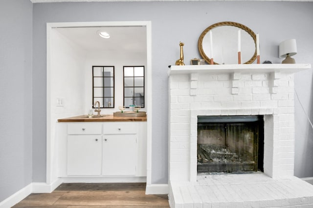 room details with a brick fireplace, sink, and hardwood / wood-style floors