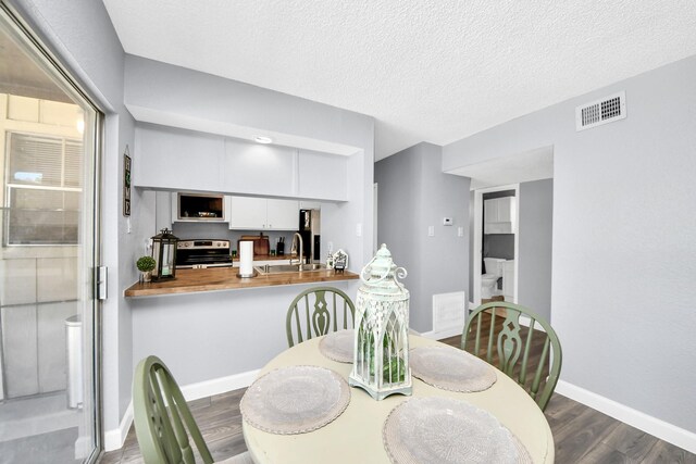 dining space with a textured ceiling, dark hardwood / wood-style flooring, and sink