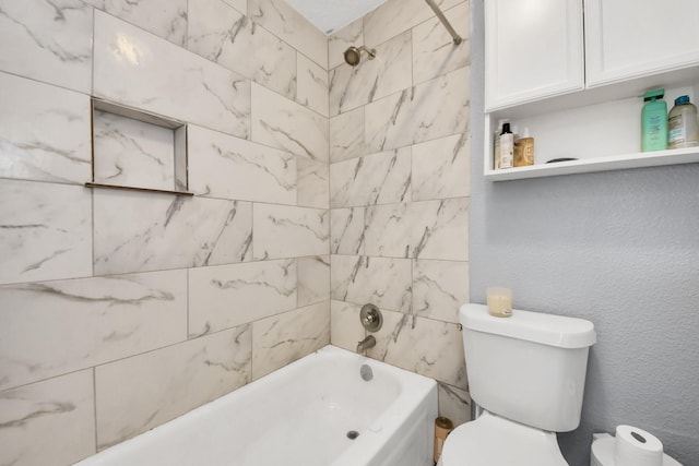 bathroom with toilet and tiled shower / bath