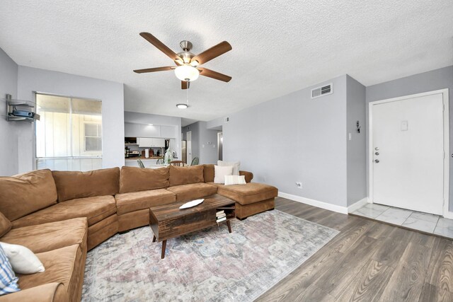 living room with ceiling fan, a textured ceiling, and hardwood / wood-style flooring