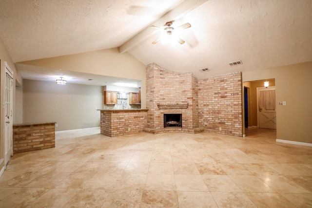 unfurnished living room featuring brick wall, a fireplace, beamed ceiling, ceiling fan, and a textured ceiling