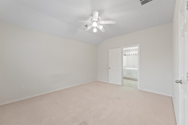 unfurnished bedroom featuring vaulted ceiling, light colored carpet, ensuite bath, and ceiling fan