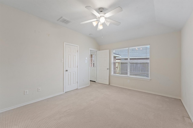 spare room with light colored carpet, vaulted ceiling, and ceiling fan