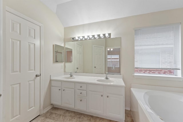 bathroom featuring vanity, a bath, and lofted ceiling