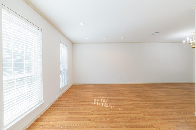 spare room with light hardwood / wood-style flooring, ornamental molding, and an inviting chandelier