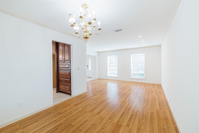 spare room with light wood-type flooring, an inviting chandelier, and ornamental molding