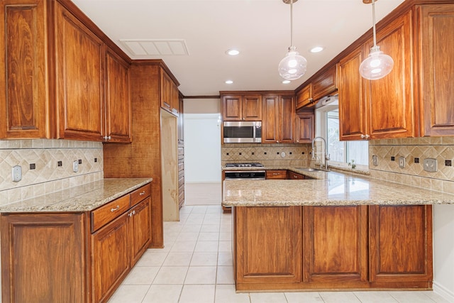 kitchen with light stone countertops, stainless steel appliances, sink, hanging light fixtures, and kitchen peninsula