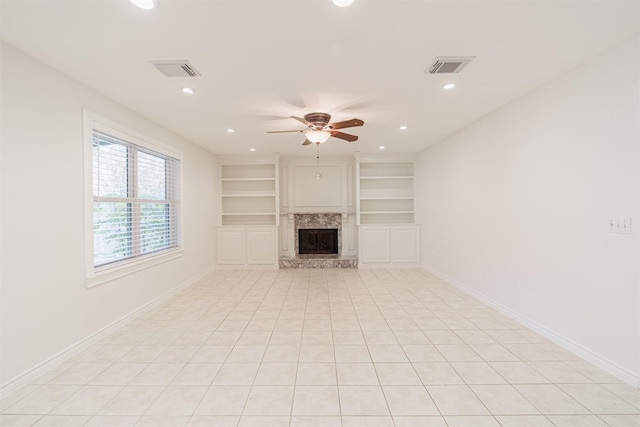 unfurnished living room featuring ceiling fan, built in shelves, light tile patterned floors, and a fireplace