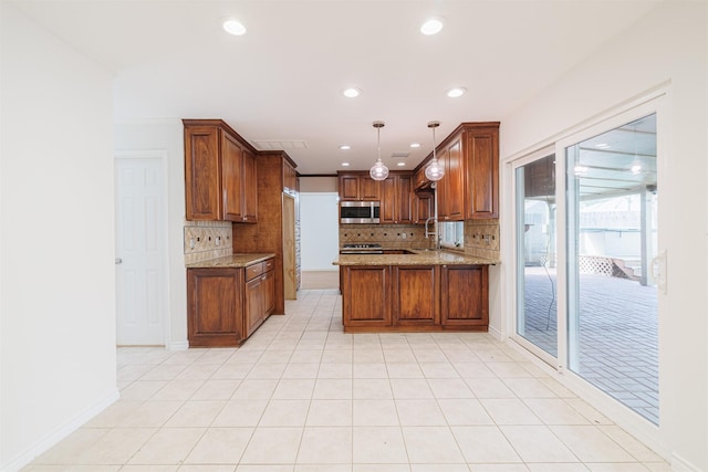 kitchen featuring kitchen peninsula, backsplash, decorative light fixtures, light stone counters, and sink