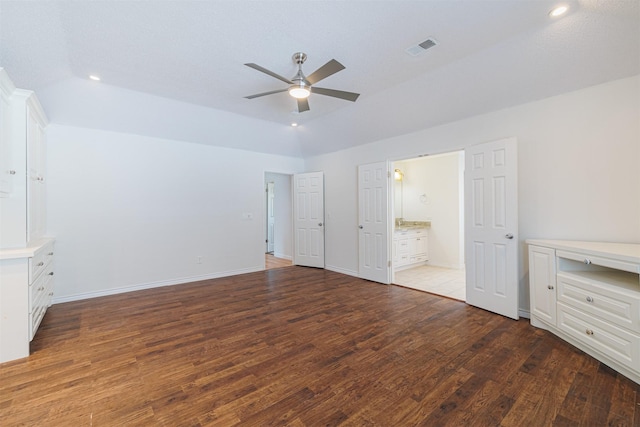 unfurnished bedroom with ceiling fan, vaulted ceiling, dark wood-type flooring, connected bathroom, and a textured ceiling