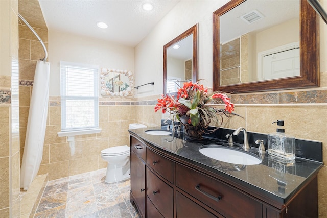 bathroom featuring toilet, vanity, tile walls, a textured ceiling, and curtained shower