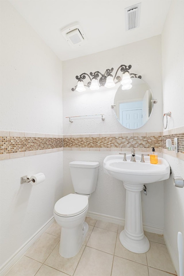 bathroom featuring toilet, tile patterned flooring, and tile walls