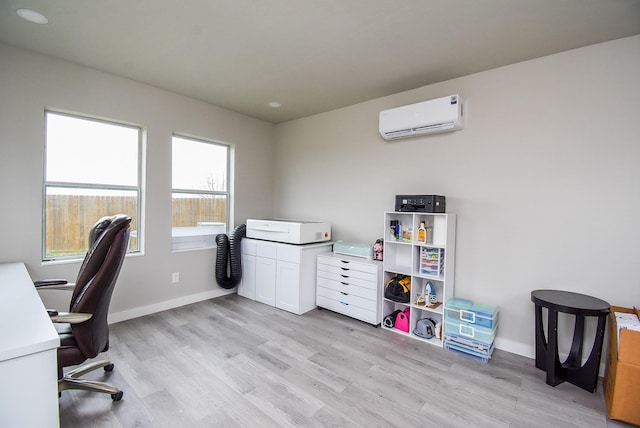 office featuring an AC wall unit, light hardwood / wood-style flooring, and a healthy amount of sunlight