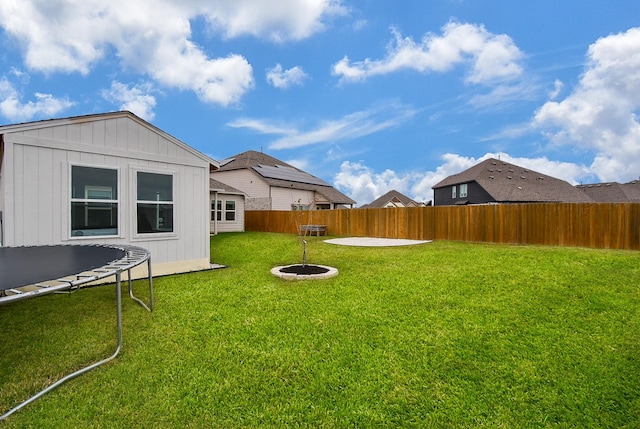 view of yard featuring a trampoline and a fire pit