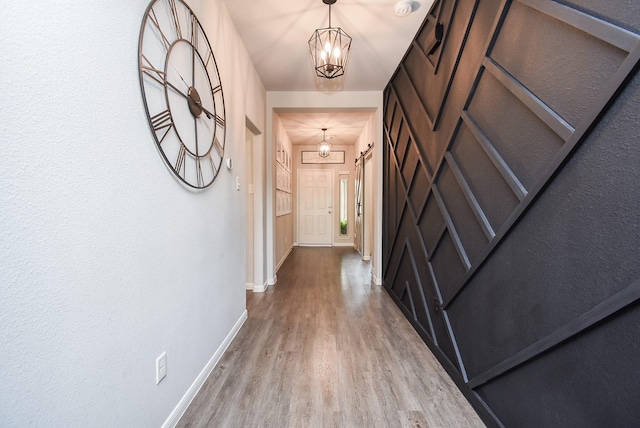 corridor with hardwood / wood-style floors and a chandelier